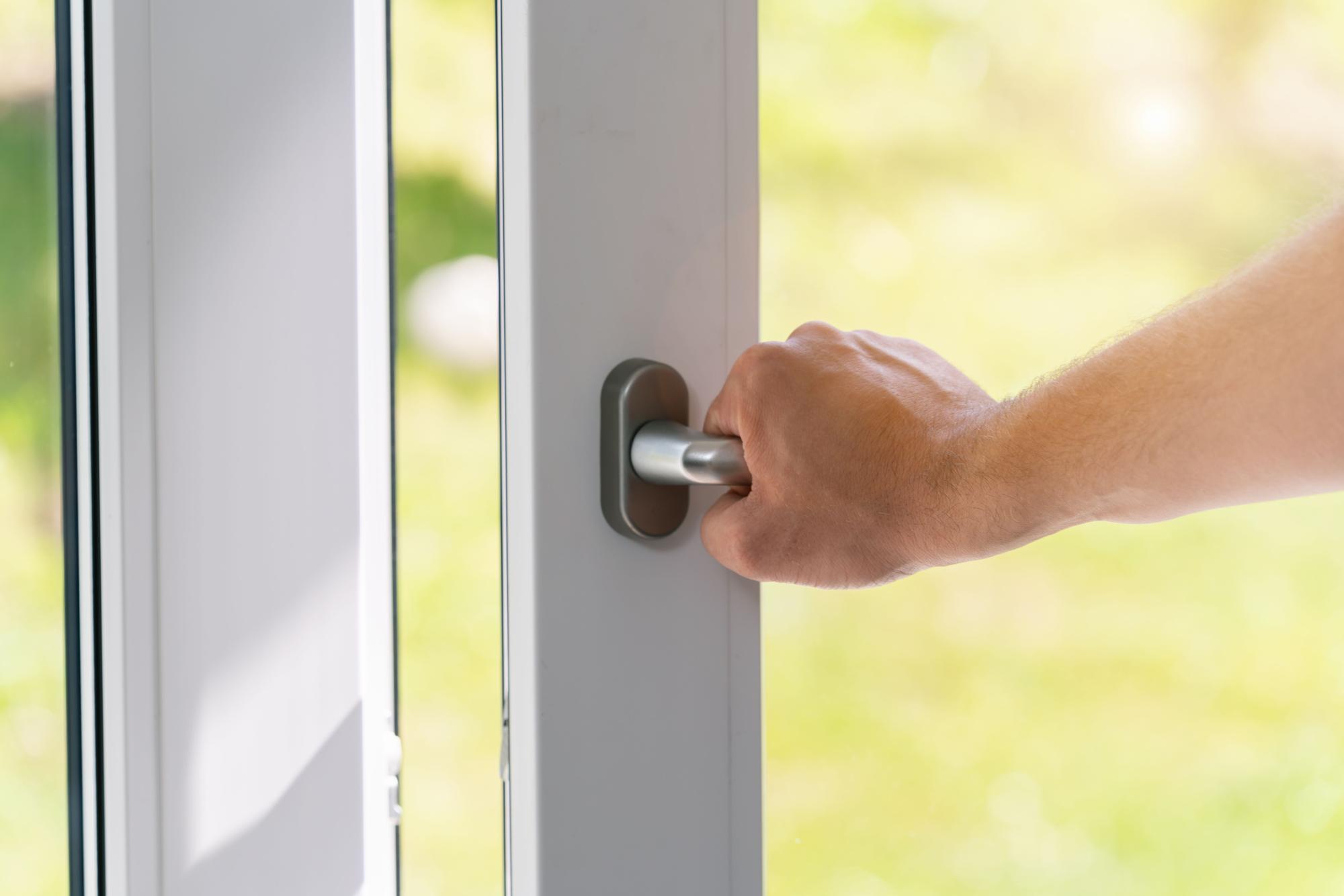 Primer plano de la mano de un hombre que comprueba que todas las puertas y ventanas de la vivienda están en buen estado y quedan bien cerradas.