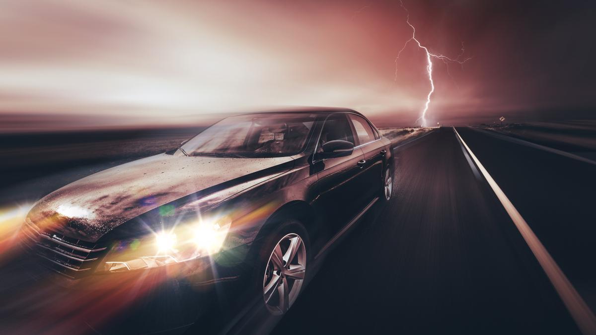 Un coche circula por una carretera durante una tormenta eléctrica.