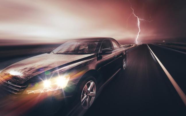 Un coche circula por una carretera durante una tormenta eléctrica.