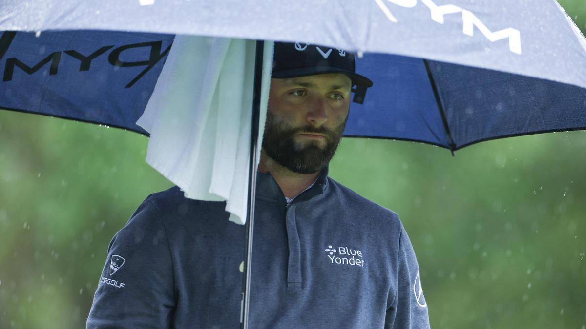 Jon Rahm se protege de la lluvia con un paraguas en Augusta.