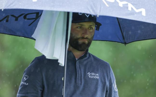Jon Rahm se protege de la lluvia con un paraguas en Augusta.