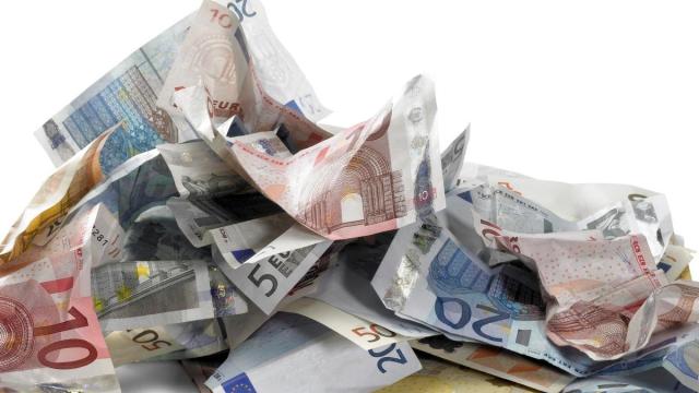 Billetes de euro arrugados sobre una mesa.