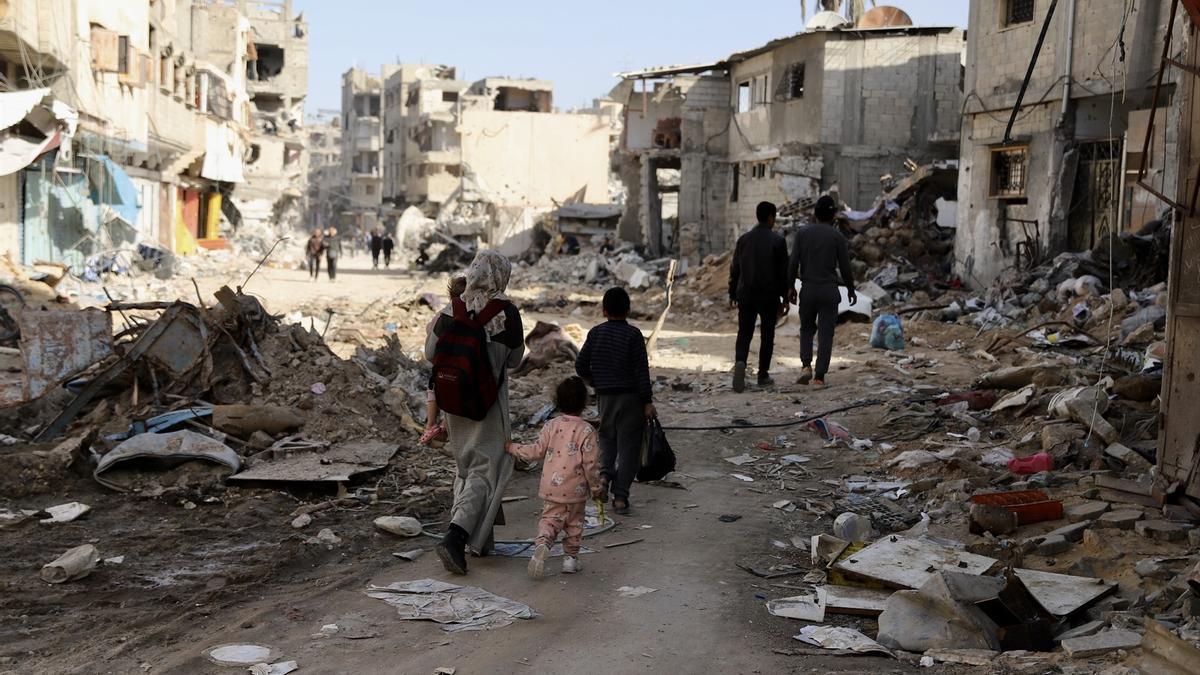 Gazatíes caminan sobre los escombros de los edificios en Gaza.
