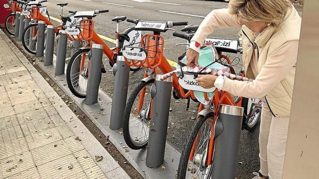 Una usuaria retira una bicicleta junto a la estación del metro de Berango