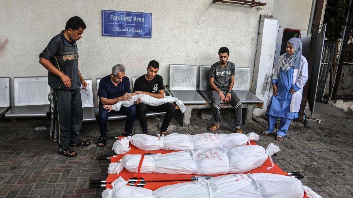 Varios palestinos velan los cuerpos de una familia asesinada en un bombardeo israelí en el hospital Najjar.