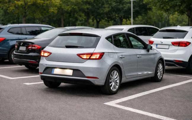 Un coche sale marcha atrás de una plaza de aparcamiento.