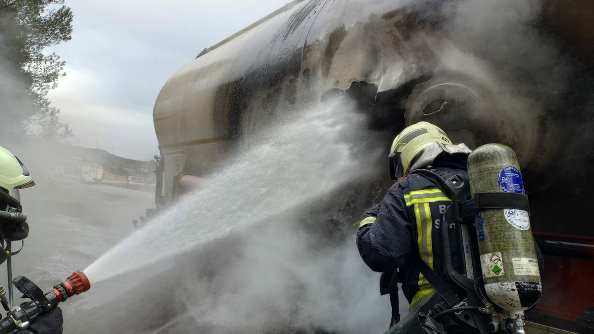 Dos bomberos atajan el fuego en el camión que transportaba biomasa