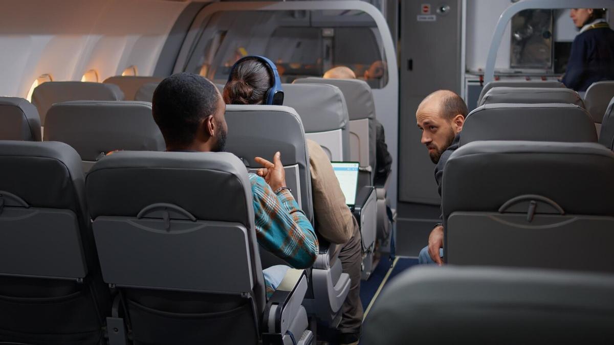 Viajeros hablando en un avión.
