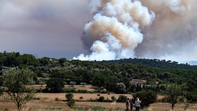 Varias personas observan el humo del incendio, en La Bisbal d'Empordà, Girona.