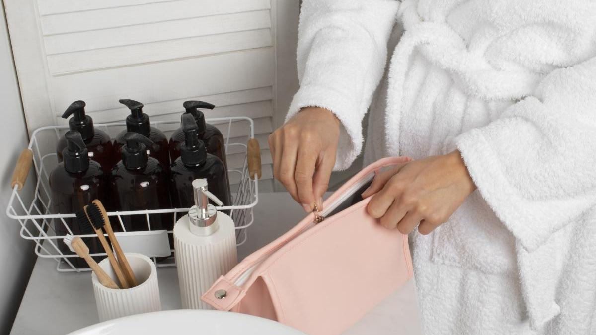 Chica utiliza un neceser de color rosa en el baño para guardar sus productos favoritos.