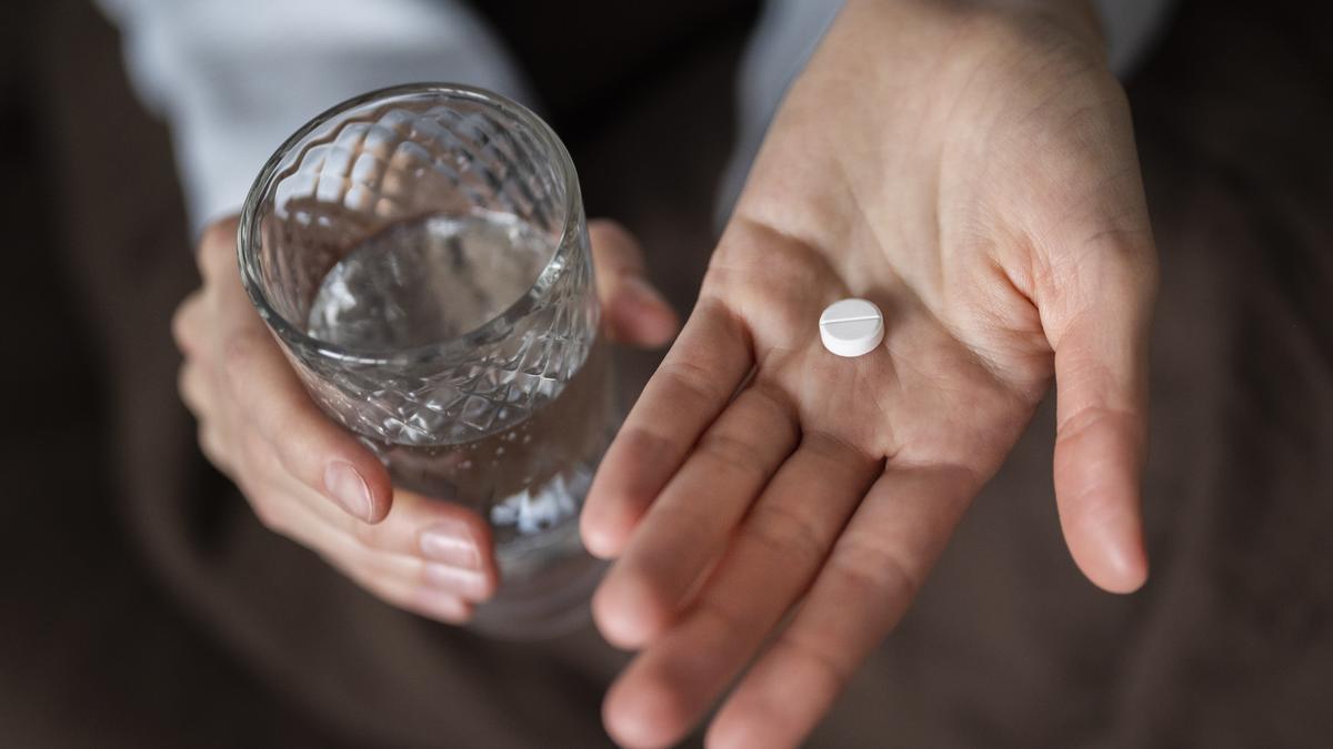 Una persona sostiene una pastilla de ibuprofeno