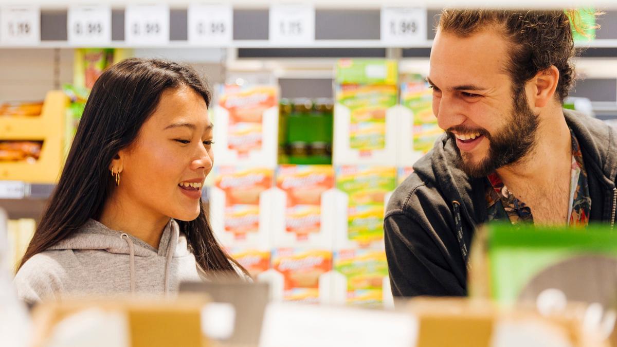 Pareja hablando entre las baldas de un supermercado.