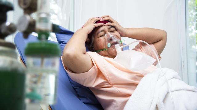 Una mujer se lleva las manos a la cabeza mientras permanece postrada en la cama del hospital, en un gesto de dolor y abatimiento.