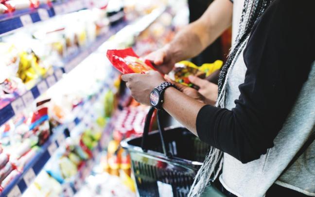 Clientes cogiendo un producto de un supermercado.