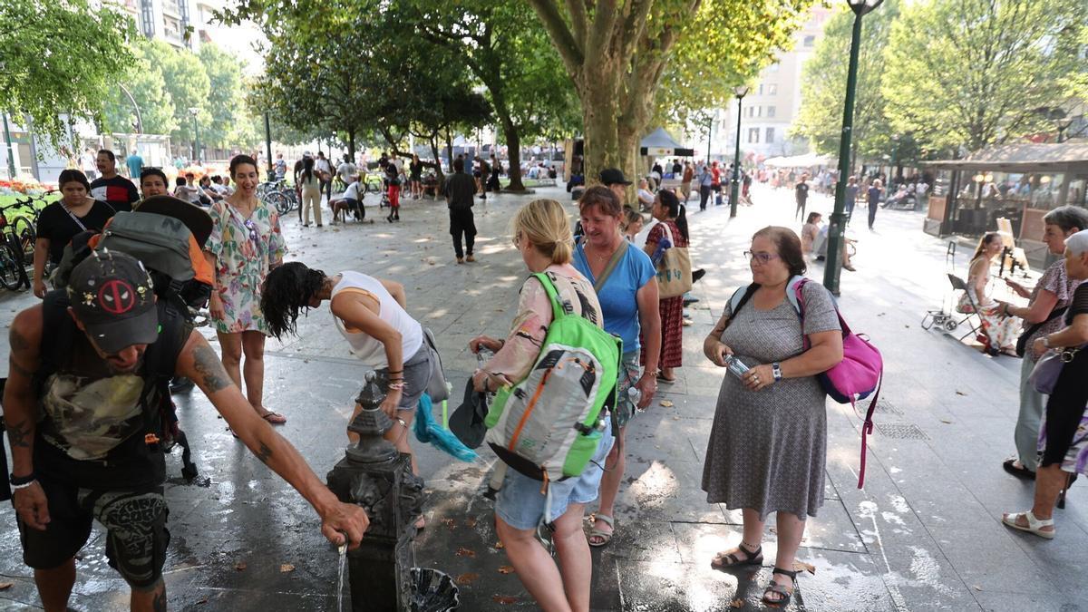 Varias personas se refrescan en una fuente en Donostia durante la ola de calor.