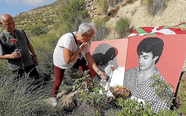 Axun Lasa deposita una rosa roja en el retrato de su hermano Joxean, en el lugar donde apareció su cuerpo junto al de Joxi Zabala. | FOTO: EFE