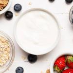 Tazón de yogur griego rodeado de frutas y cereales.