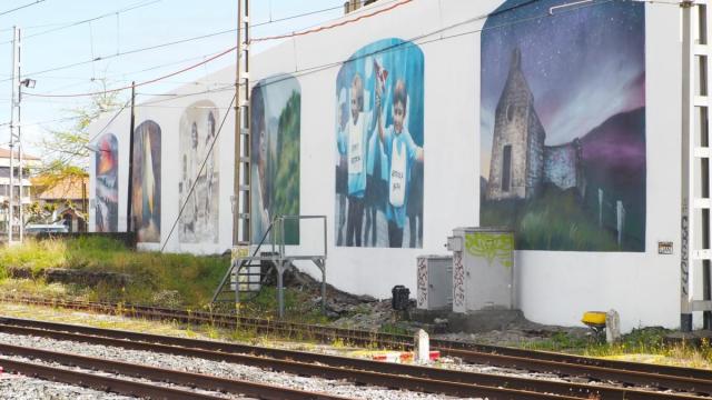El mural, pintado en la fachada posterior del Paseo Cubierto, recibe a los viajeros que llegan en tren a Deba.