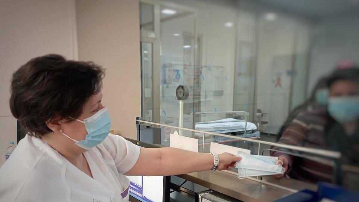 Una sanitaria facilita mascarillas a un usuario.
