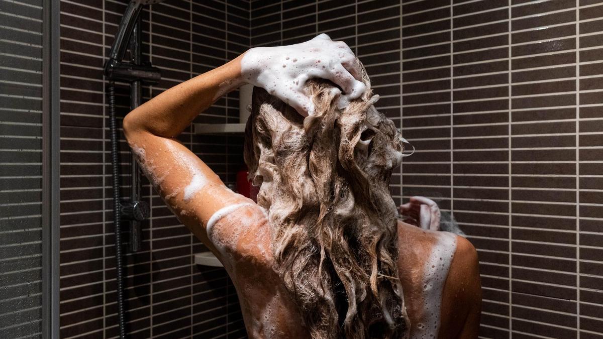 Una mujer se lava la melena con mechas en la ducha.