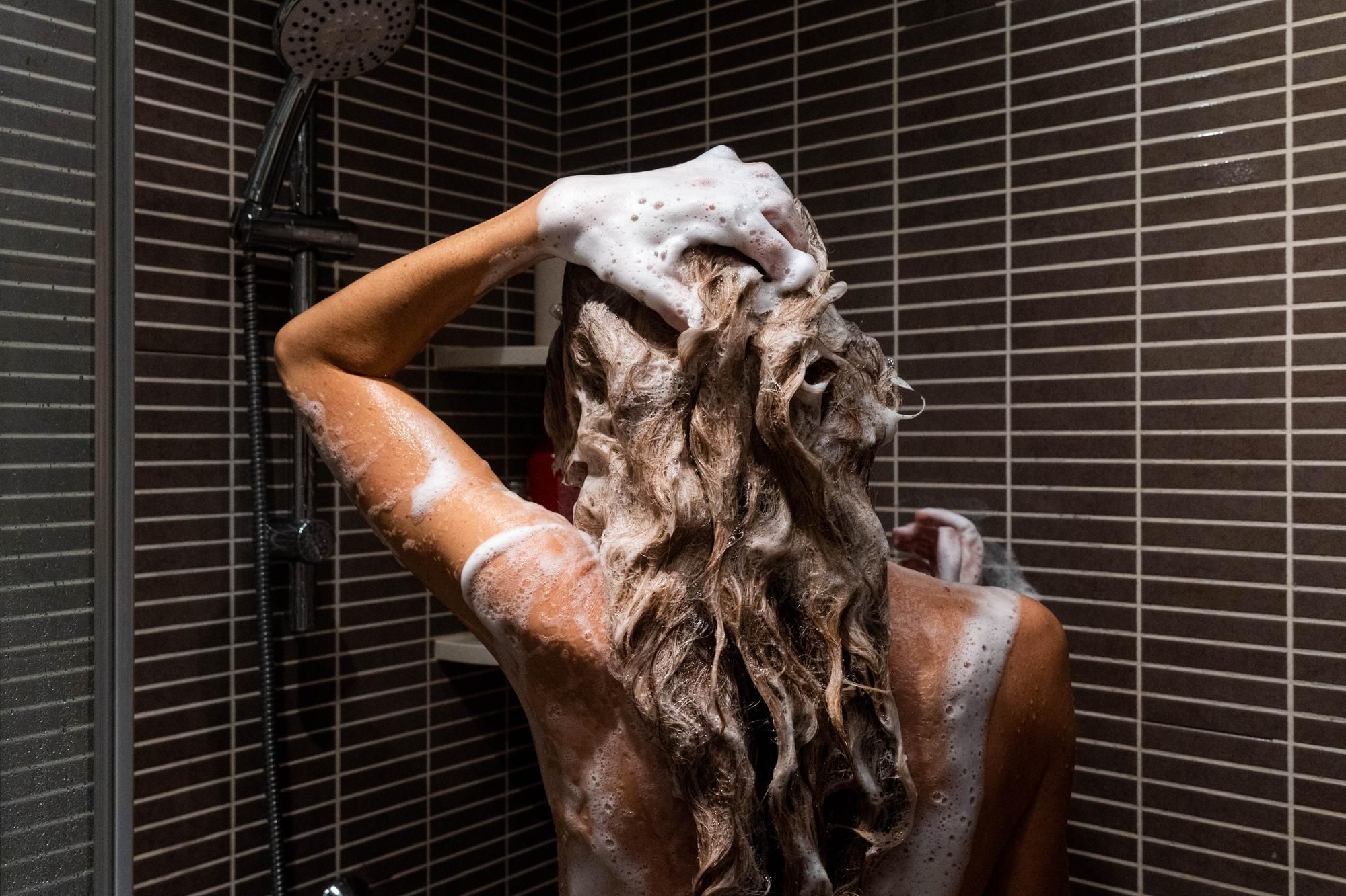 Una mujer se lava la melena con mechas en la ducha.
