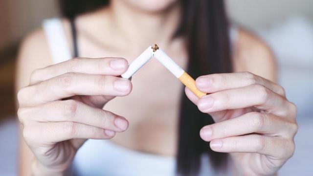 Una mujer rompe un cigarrillo, manifestando así su intención de dejar de fumar.