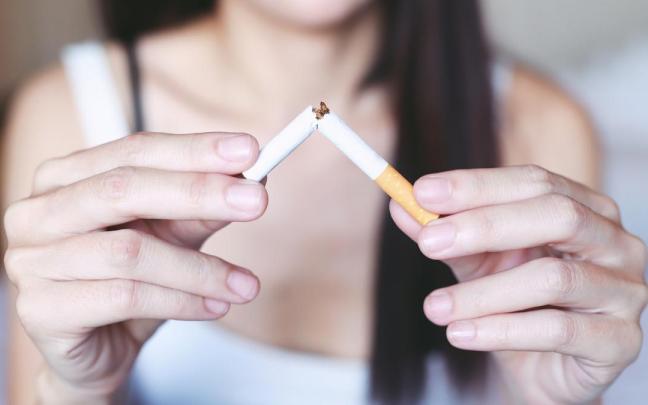 Una mujer rompe un cigarrillo, manifestando así su intención de dejar de fumar.