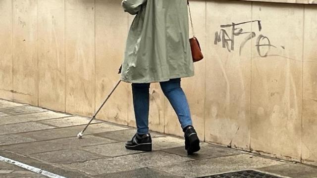 Persona invidente camina por la calle con la ayuda de un bastón.