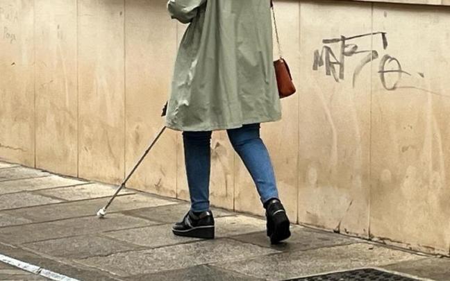 Persona invidente camina por la calle con la ayuda de un bastón.