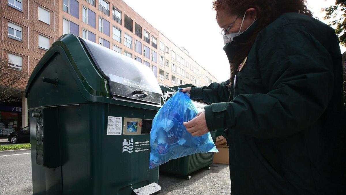 Una mujer tira la basura a un contenedor con sistema de tarjeta