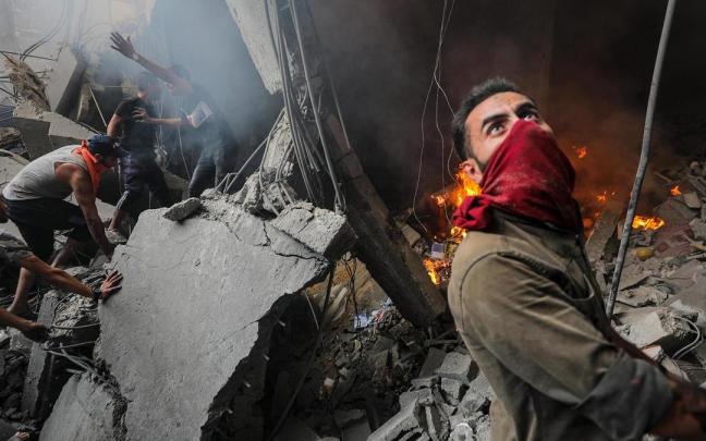 Palestinos entre los escombros tras un ataque israelí al campo de refugiados de Al-Shati