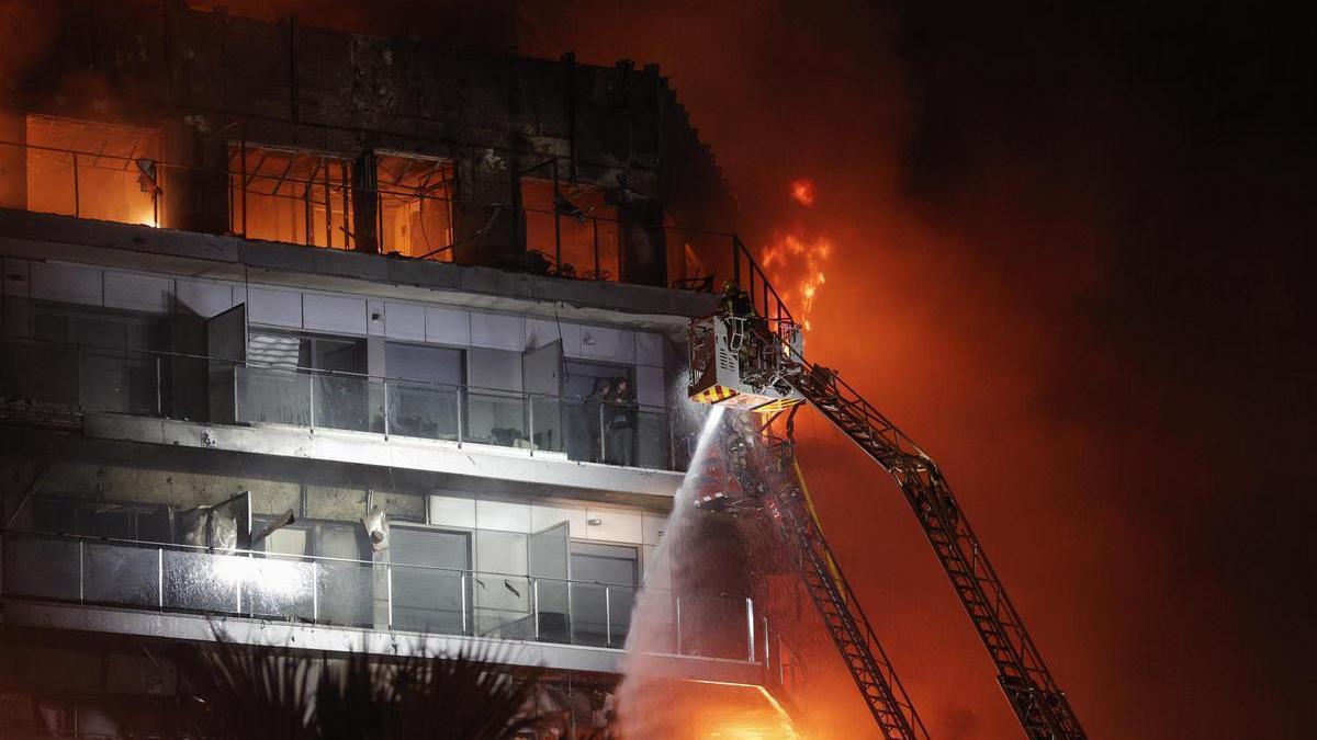 Los bomberos intentan rescatar a vecinos atrapados por el fuego en Valencia.