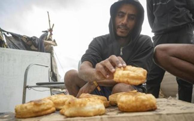 Migrante cocina, en la playa de Trampolín, a 19 de septiembre de 2026, en Ceuta.