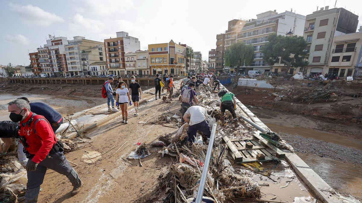 Decenas de voluntarios trabajan para despejar uno de los puentes de Paiporta.