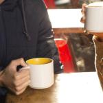 Grupo de personas disfrutan de una bebida caliente en la terraza de un bar mientras sonríen y mantienen una conversación agradable