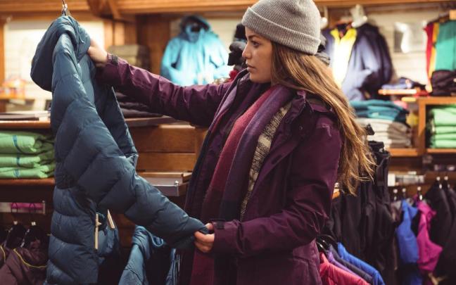Una mujer mira un abrigo en una tienda de ropa.