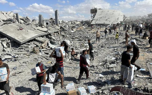 Los gazatíes cargan con cajas de ayuda humanitaria en Jan Yunis.