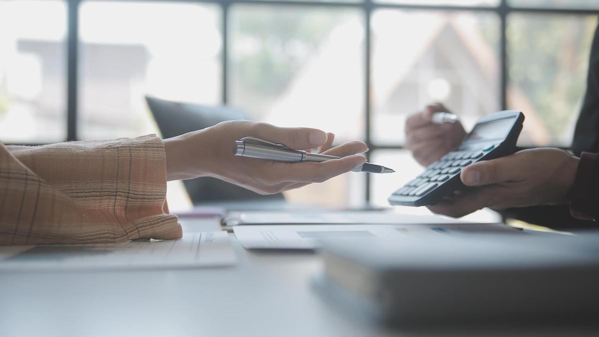 Un empleado de banca muestra la cuota de un préstamo en una calculadora.