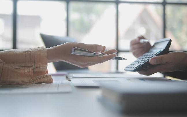 Un empleado de banca muestra la cuota de un préstamo en una calculadora.