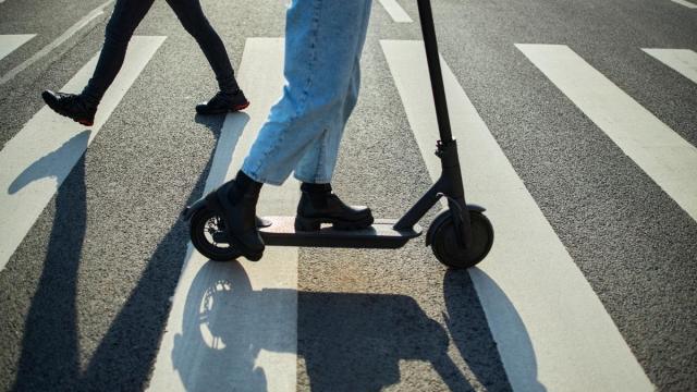 Una usuaria de un patinete eléctrico cruza un paso de peatones.