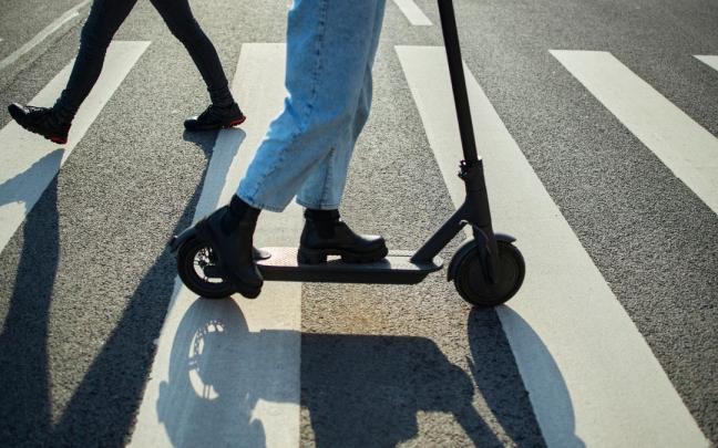 Una usuaria de un patinete eléctrico cruza un paso de peatones.