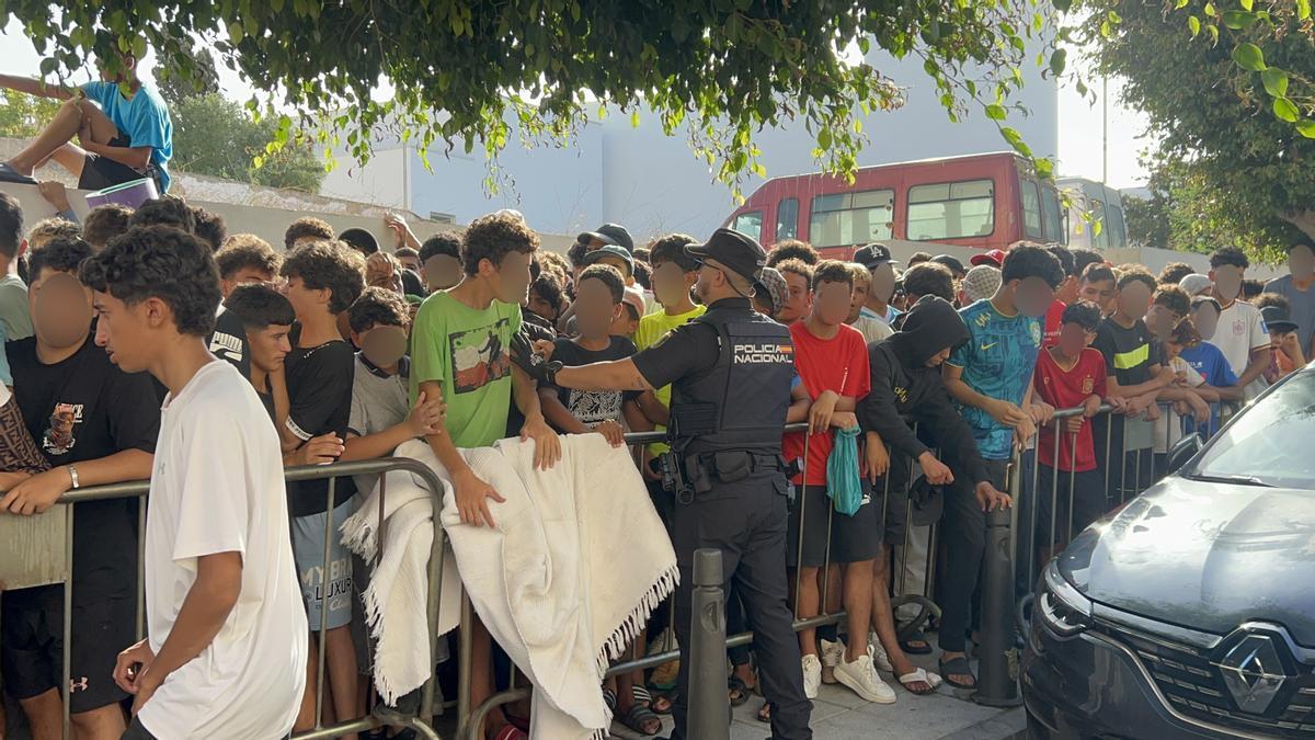 Menores migrantes esperan a las puertas de la Jefatura Superior de Policía de Ceuta para que les registren.