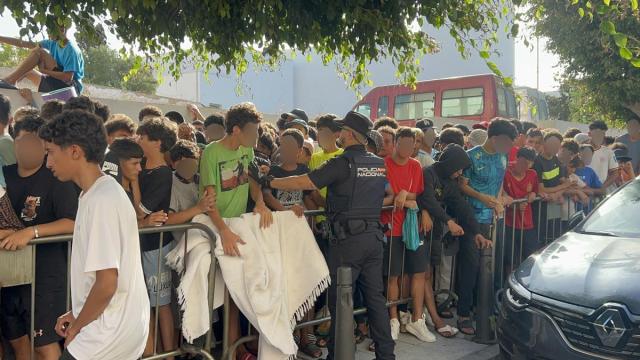 Menores migrantes esperan a las puertas de la Jefatura Superior de Policía de Ceuta para que les registren.