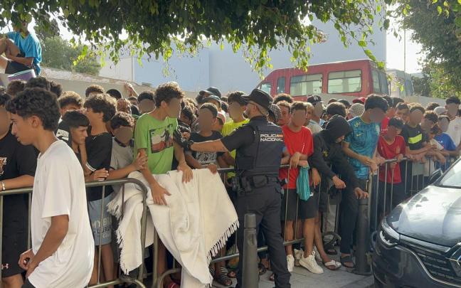 Menores migrantes esperan a las puertas de la Jefatura Superior de Policía de Ceuta para que les registren.