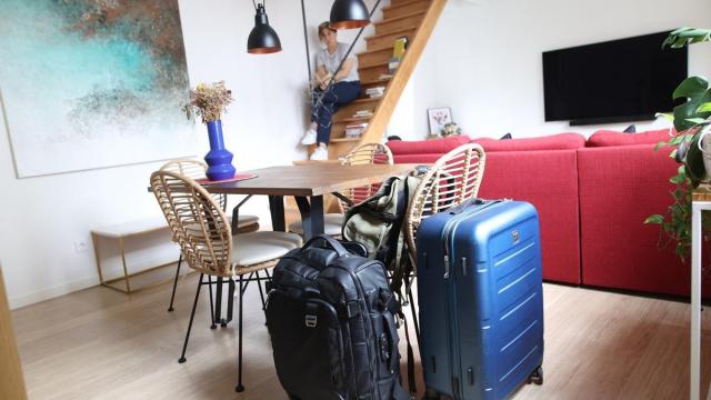Una viajera, al fondo, en el salón de un apartamento con las maletas en primer plano. / Borja Guerrero Una viajera, al fondo, en el salón de un apartamento con las maletas en primer plano.