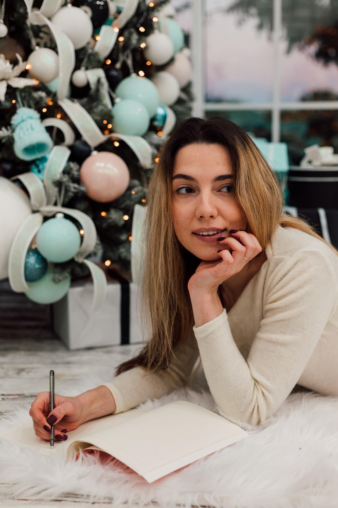 Una mujer escribe sus propósitos junto al árbol de Navidad.