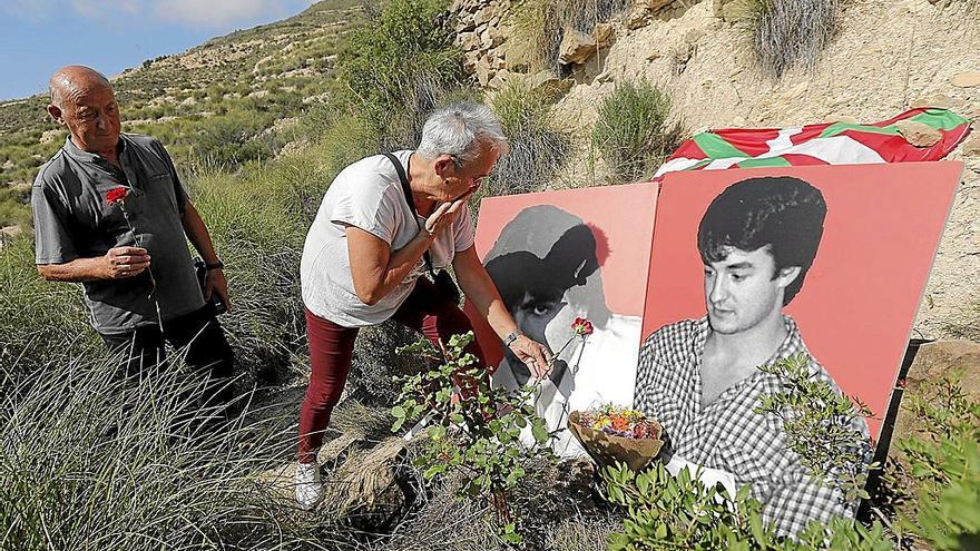 Axun Lasa deposita una rosa roja en el retrato de su hermano Joxean, en el lugar donde apareció su cuerpo junto al de Joxi Zabala. | FOTO: EFE
