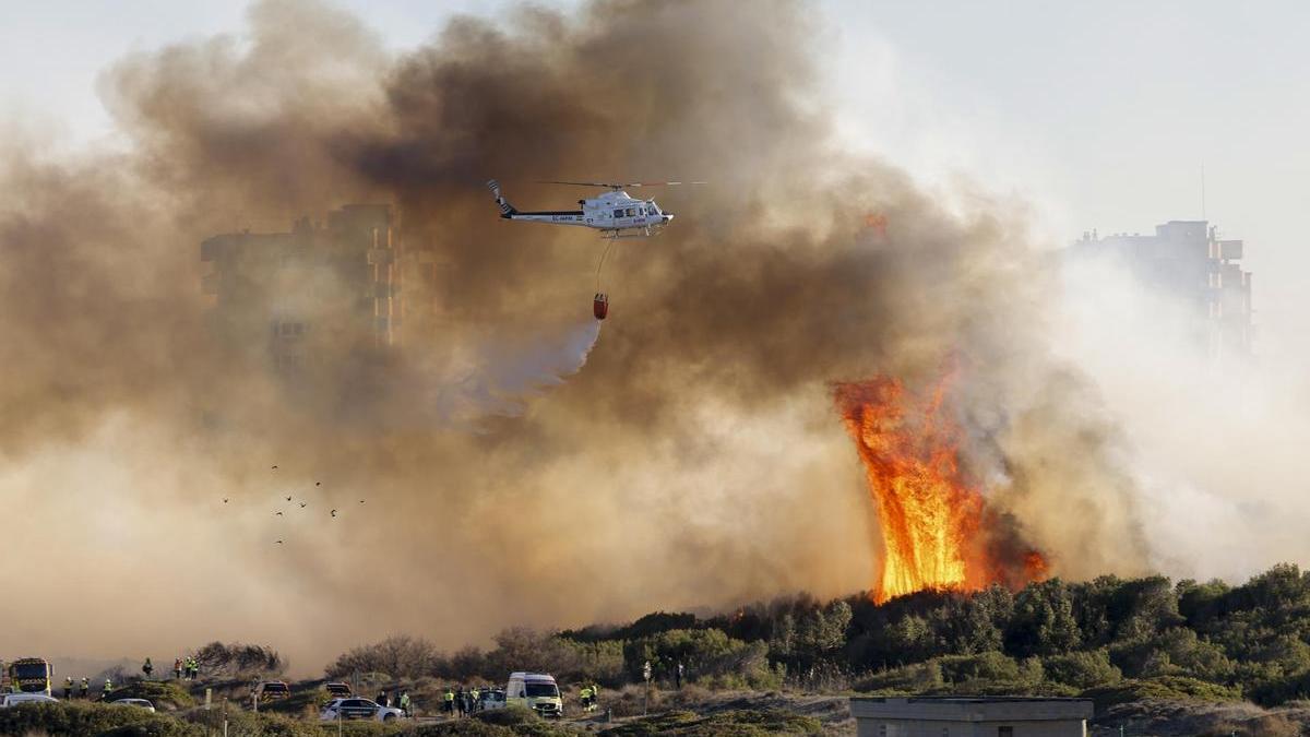 Un helicóptero trabaja en las labores de extinción del incendio forestal declarado en El Saler, en Valencia.