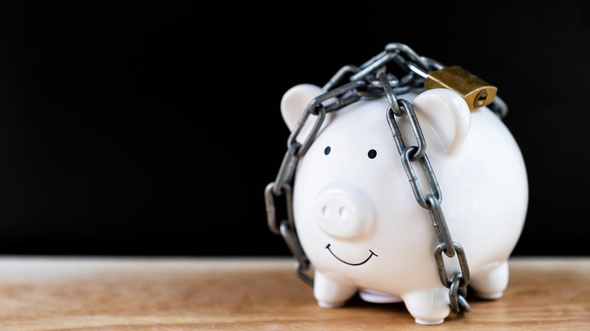 Una hucha con ahorros bloqueada por una cadena y un candado.