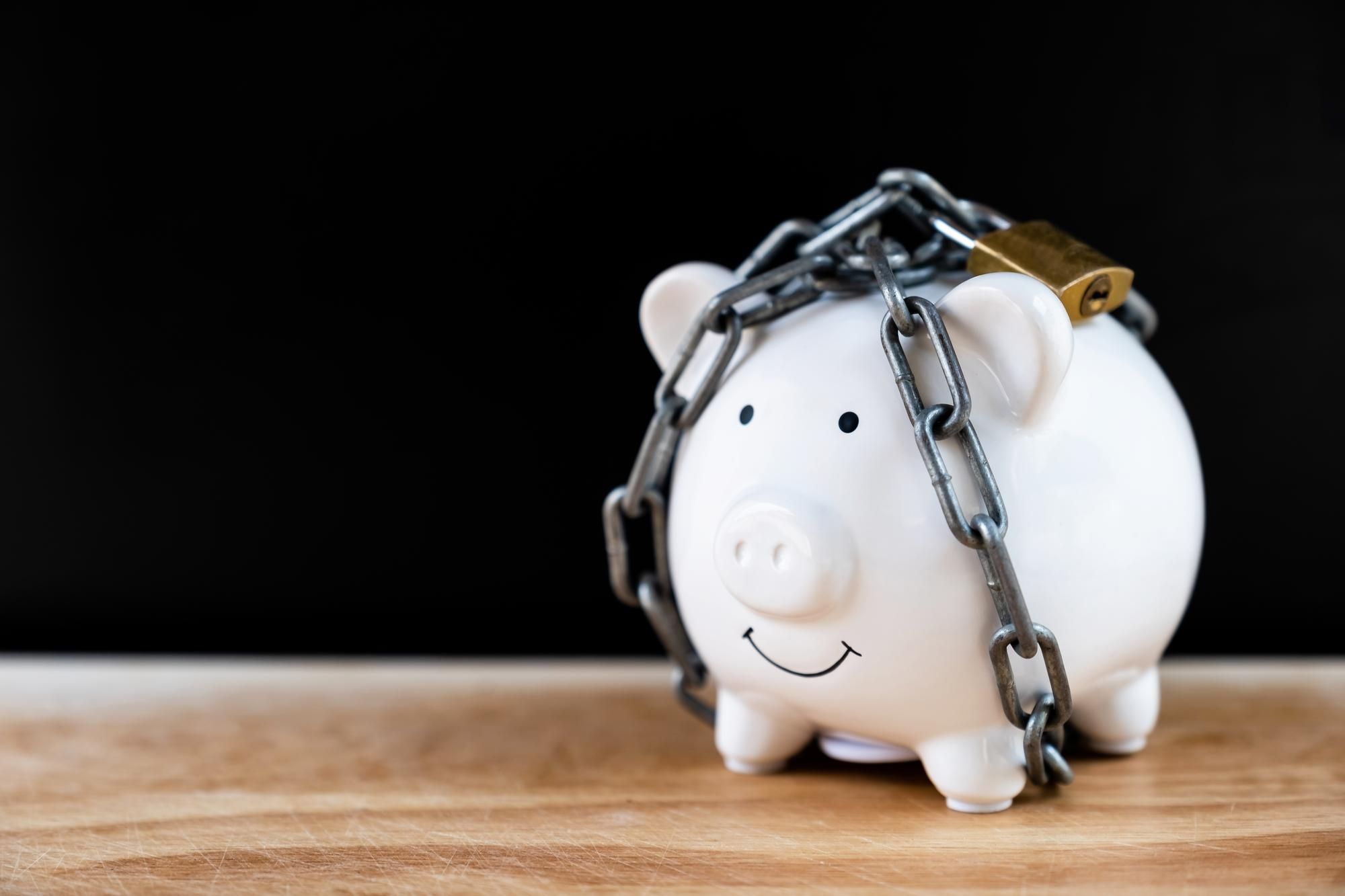 Una hucha con ahorros bloqueada por una cadena y un candado.